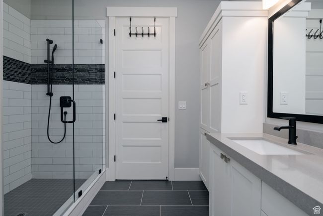 Bathroom with a stall shower, vanity, tile patterned flooring, and baseboards | Image 22