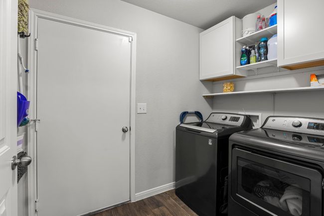 Laundry area featuring cabinet space, washer and dryer, and dark wood-style floors | Image 21