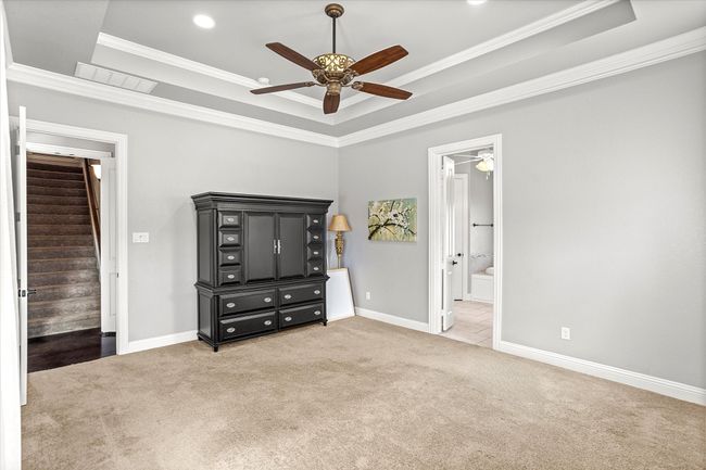 Unfurnished bedroom with carpet, a raised ceiling, crown molding, baseboards, and ensuite bath | Image 18
