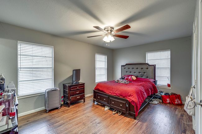 Bedroom with a textured ceiling, a ceiling fan, baseboards, and wood finished floors | Image 5