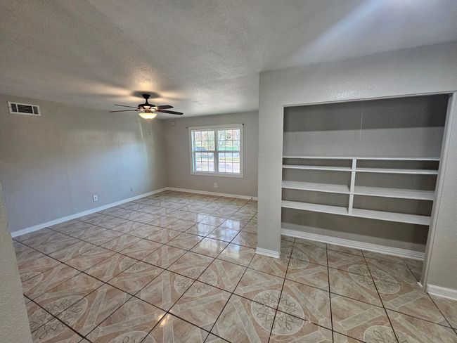Unfurnished room with a textured ceiling, a ceiling fan, built in features, and light tile patterned floors | Image 28