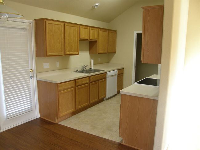 Kitchen featuring white dishwasher, lofted ceiling, light countertops, and light wood-style floors | Image 7