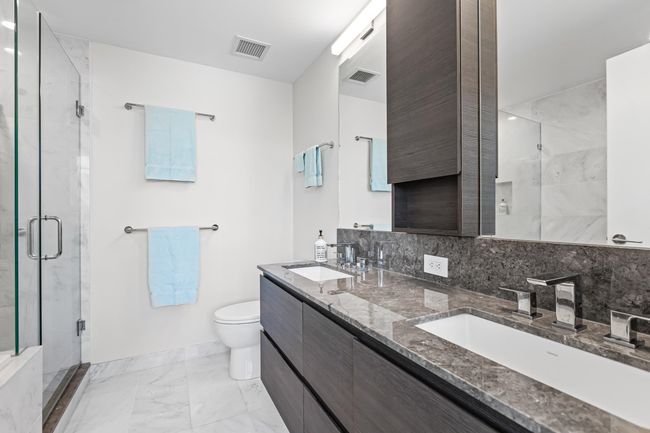 Bathroom featuring a shower stall, toilet, a sink, and visible vents | Image 16