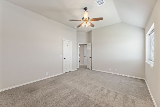 Large bedroom featuring carpet flooring, vaulted ceiling, and a ceiling fan | Image 31