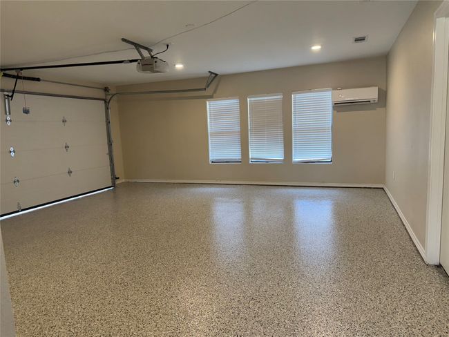 Garage with a wall mounted AC, a garage door opener, and recessed lighting | Image 39
