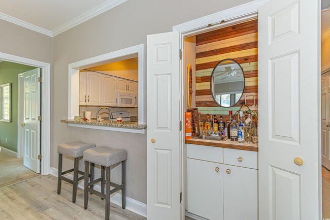 Kitchen with a breakfast bar area, ornamental molding, a sink, light wood-style flooring, and white microwave | Image 5