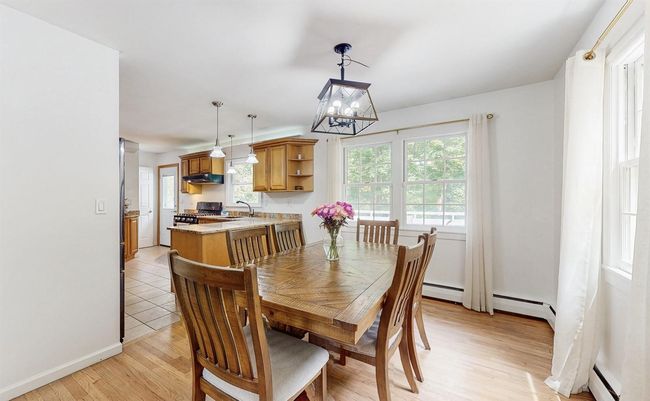 Dining room with light wood finished floors, a beautiful light fixture, baseboard heating. | Image 11