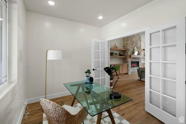 Home office featuring french doors, baseboards, recessed lighting, wood finished floors, and a stone fireplace | Image 14