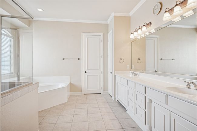 Full bath with a garden tub, double vanity, ornamental molding, tile patterned floors, and an enclosed shower | Image 23