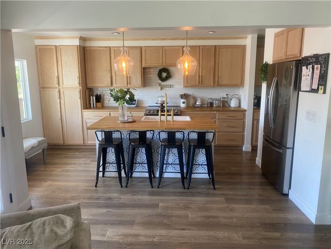 Kitchen featuring stainless steel refrigerator with ice dispenser, a sink, dark wood-style flooring, and decorative backsplash | Image 29