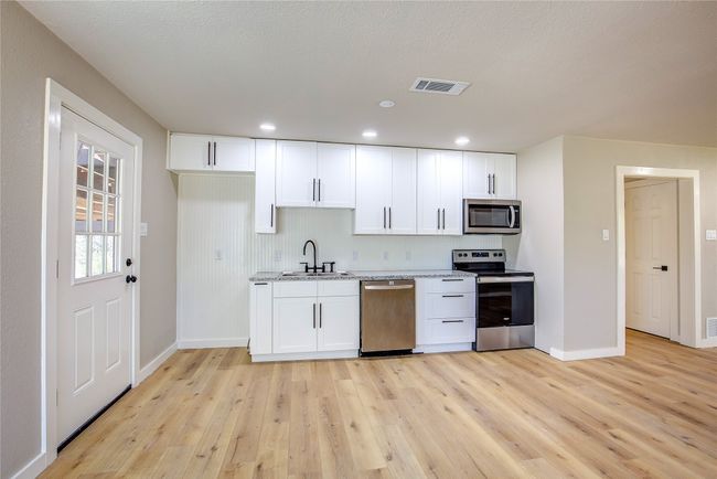 Kitchen with a sink, light wood-style floors, stainless steel appliances, baseboards, and visible vents | Image 9