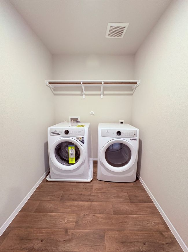 Laundry room with washing machine and dryer, wood finished floors, visible vents, and laundry area | Image 27