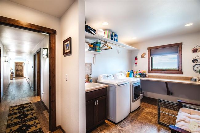The laundry room has utility sink, folding space, and is located just off the garage | Image 21