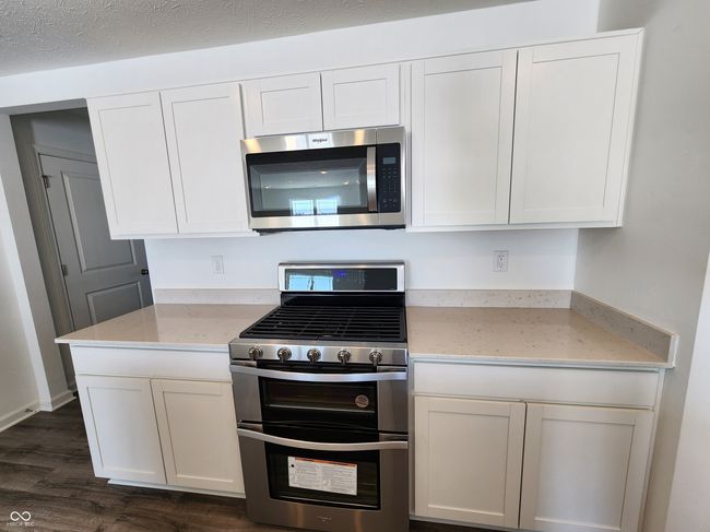 hall featuring dark wood-style floors, visible vents, and baseboards | Image 5