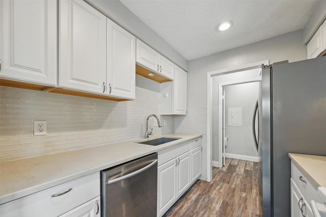 Kitchen with stainless steel appliances, dark wood-style flooring, white cabinetry, decorative backsplash, and recessed lighting | Image 9