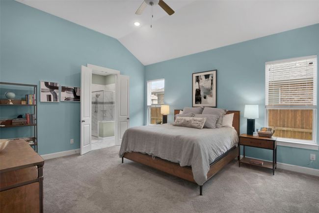 Carpeted bedroom with vaulted ceiling, baseboards, ceiling fan, and ensuite bath | Image 12