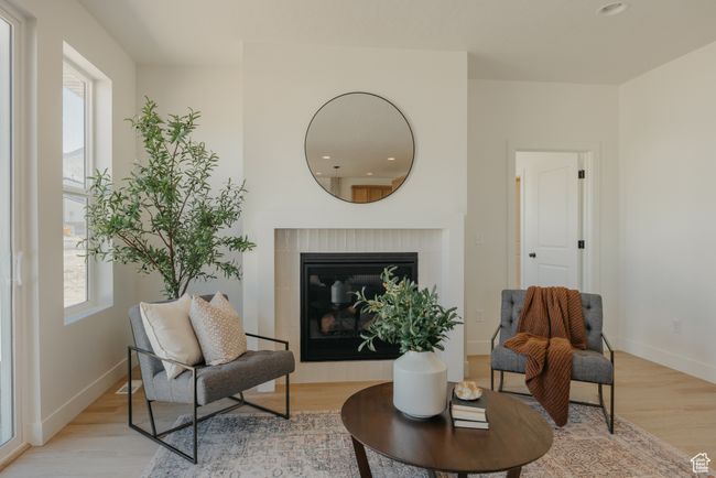 Living area with light wood-style flooring, recessed lighting, a glass covered fireplace, and baseboards | Image 11
