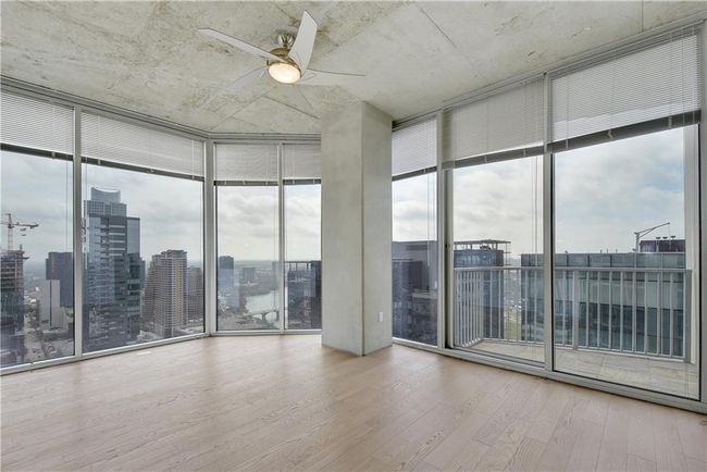 Unfurnished room with wood finished floors, a view of city, ceiling fan, and a wall of windows | Image 9