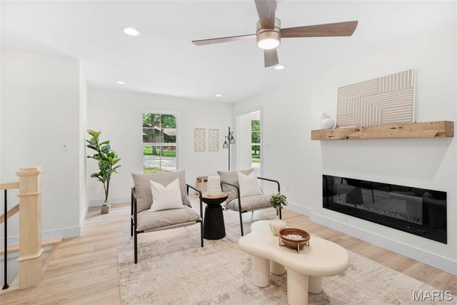 Living area with light wood finished floors, recessed lighting, ceiling fan, and a glass covered fireplace | Image 10
