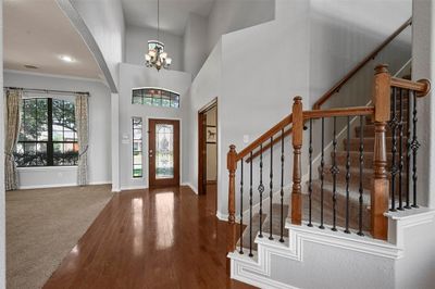 Entrance foyer featuring hardwood / wood-style flooring, crown molding, a notable chandelier, and a healthy amount of sunlight | Image 2