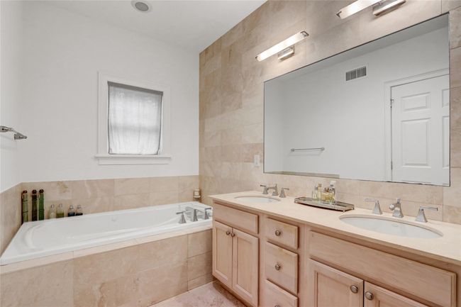 Bathroom featuring double vanity, a bath, and tile walls | Image 17