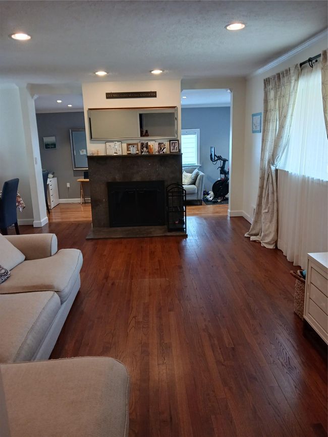 Living room with dark wood finished floors, baseboards, a fireplace with raised hearth, and recessed lighting | Image 8