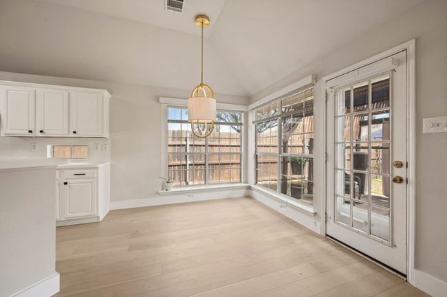 Unfurnished dining area featuring an inviting chandelier, light wood-style floors, lofted ceiling, and visible vents | Image 12