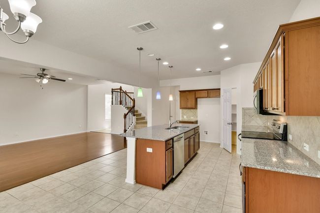Kitchen featuring stainless steel appliances, open floor plan, recessed lighting, brown cabinets, and light tile patterned floors | Image 10