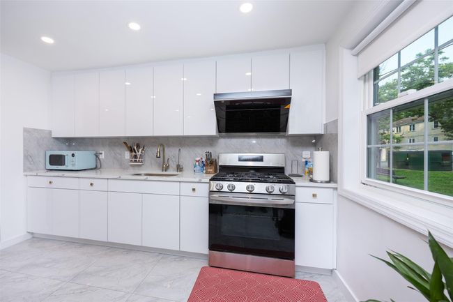 Kitchen featuring stainless steel range with gas stovetop, a sink, light marble finish flooring, white microwave, and recessed lighting | Image 10
