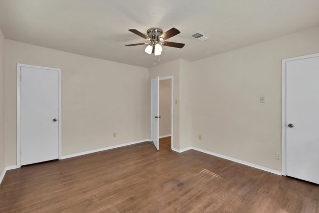 Another view of the front bedroom with a textured ceiling, a ceiling fan, hardwood flooring and two closets | Image 24