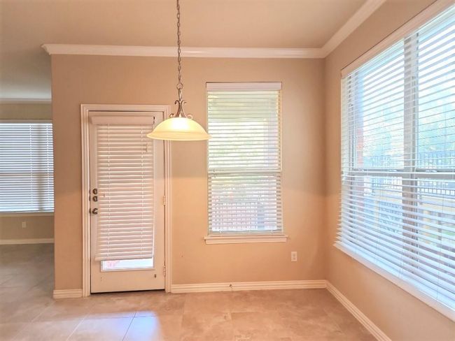 Unfurnished dining area with light tile patterned flooring, healthy amount of natural light, crown molding, and baseboards | Image 12