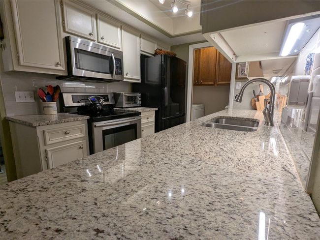 Kitchen with appliances with stainless steel finishes, light stone counters, and white cabinetry | Image 13