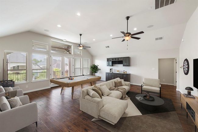 This expansive game room is an entertainer’s dream, featuring rich hardwood floors, a stylish built-in bar area, and French doors that open to a private balcony for seamless indoor-outdoor enjoyment. *This photo has been virtually staged.* | Image 29