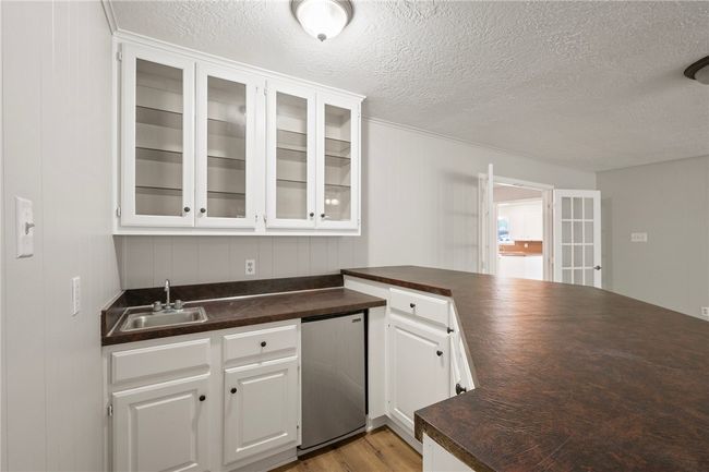 Kitchen featuring a sink, refrigerator, a textured ceiling, a peninsula, and white cabinetry | Image 10