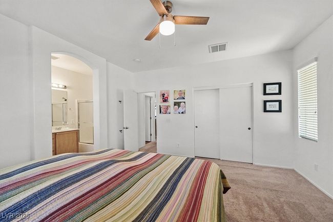 Bedroom with arched walkways, light carpet, a closet, ensuite bathroom, and ceiling fan | Image 16