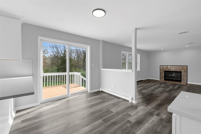 Unfurnished living room featuring dark wood-style floors, plenty of natural light, visible vents, and a baseboard radiator | Image 7