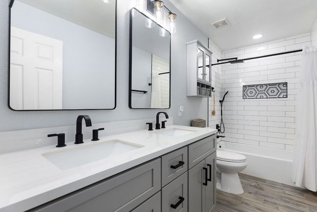 Full bathroom featuring double vanity, toilet, wood finished floors, shower / bath combination with curtain, and recessed lighting | Image 30