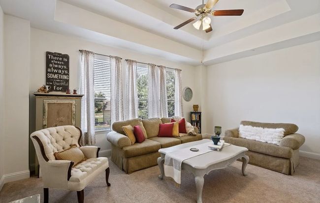 Living room with ceiling fan, baseboards, light colored carpet, and a tray ceiling | Image 21