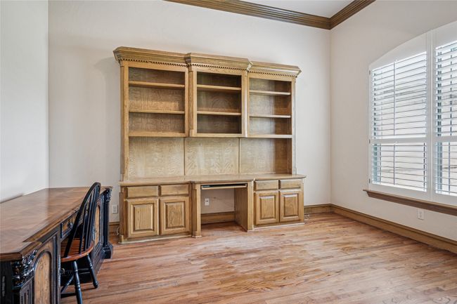 Office/study with hardwood floors, crown moulding and plantation shutters facing the front of the house. | Image 18