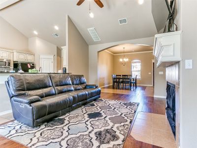 Living room featuring light hardwood / wood-style flooring, high vaulted ceiling, ceiling fan with notable chandelier, and ornamental molding | Image 3