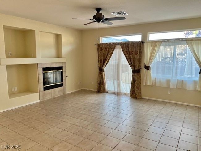 Unfurnished living room featuring visible vents, a fireplace, baseboards, ceiling fan, and light tile patterned floors | Image 5