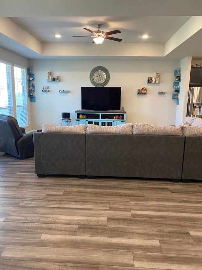 Living area with recessed lighting, a raised ceiling, wood finished floors, and a ceiling fan | Image 4