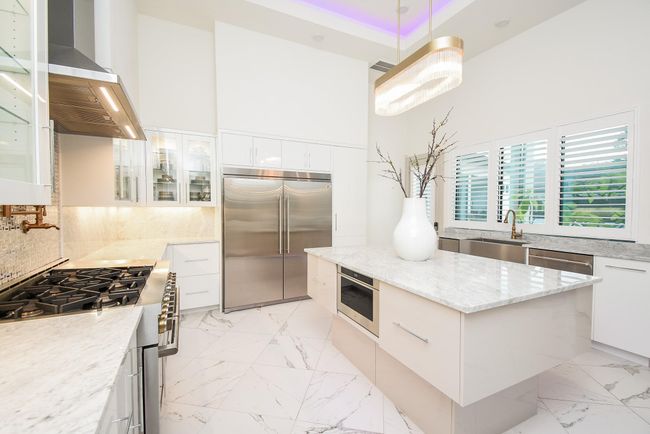 Chefs kitchen features Carrara White marble countertops, oversized custom cabinetry, feature pendant lighting, ambient lighting and luxury finishes. | Image 16