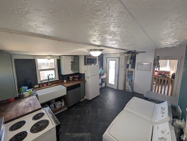 Kitchen featuring independent washer and dryer, a textured ceiling, a sink, and appliances with stainless steel finishes | Image 12