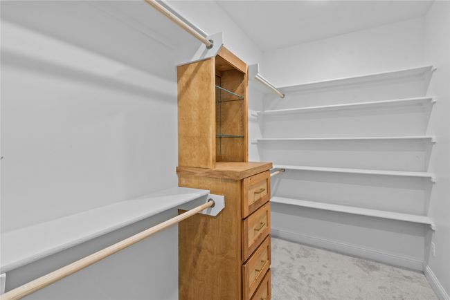 Walk in closet featuring light colored carpet | Image 15
