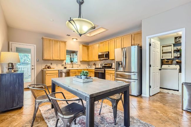 Kitchen featuring appliances with stainless steel finishes, washer / dryer, light brown cabinetry, and healthy amount of natural light | Image 7