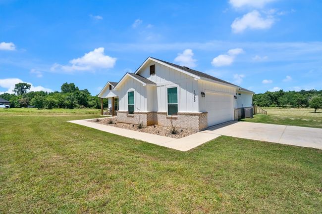 Modern inspired farmhouse featuring board and batten siding, driveway, an attached garage, and a front lawn | Image 4