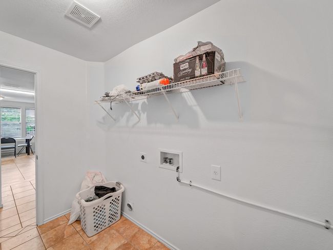 Clothes washing area with washer hookup, electric dryer hookup, light tile patterned floors, and baseboards | Image 30