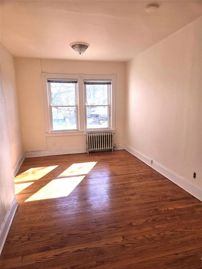 Spare room with radiator, wood finished floors, a smoke detector, and baseboards | Image 15