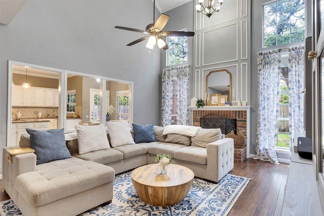 Living room featuring a towering ceiling, a ceiling fan, plenty of natural light, and dark wood-style flooring | Image 18
